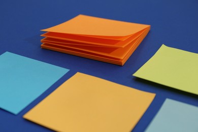 Colorful sticky notes on blue background, closeup