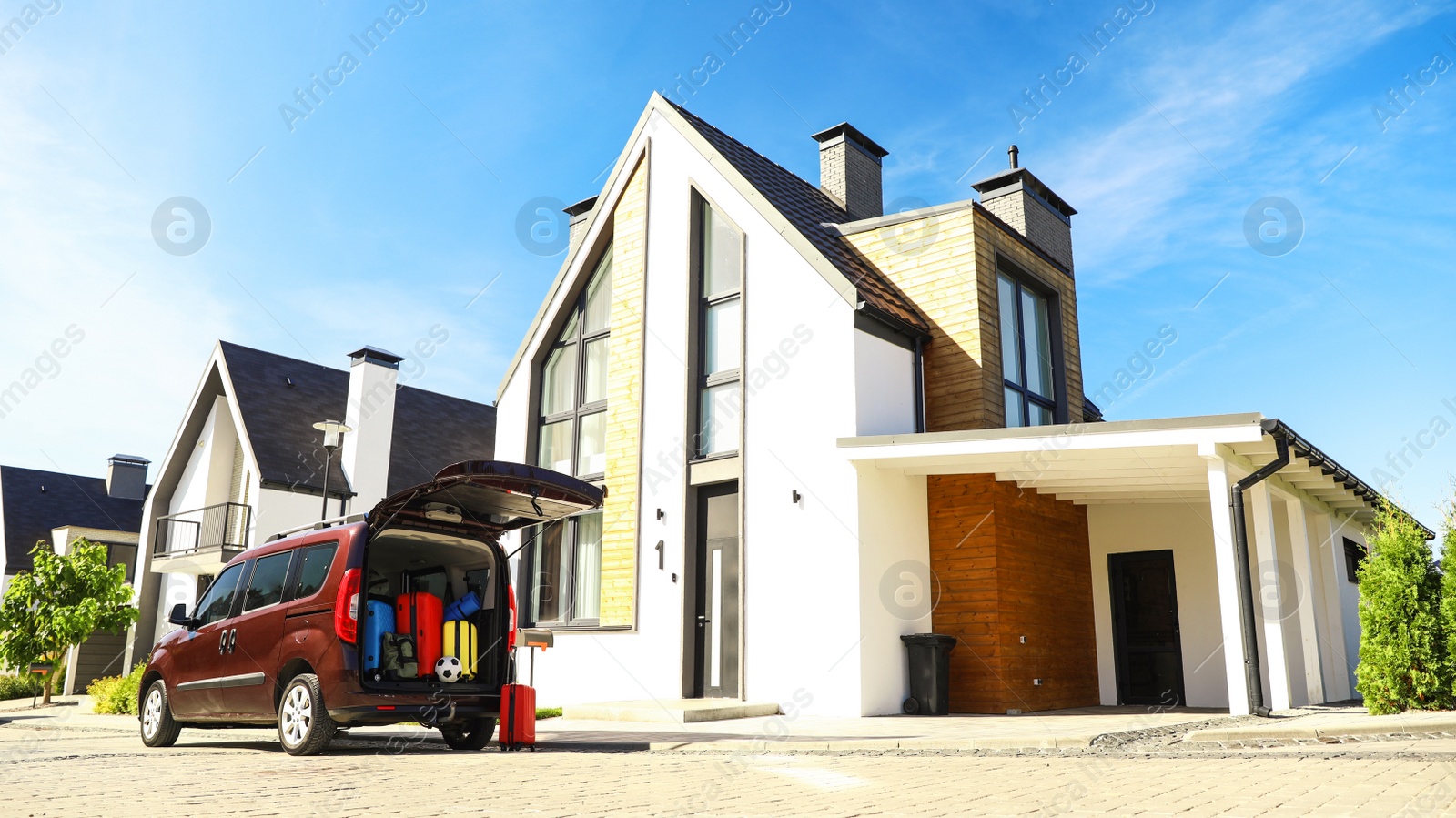 Photo of Car with suitcases in trunk near modern house outdoors. Moving day