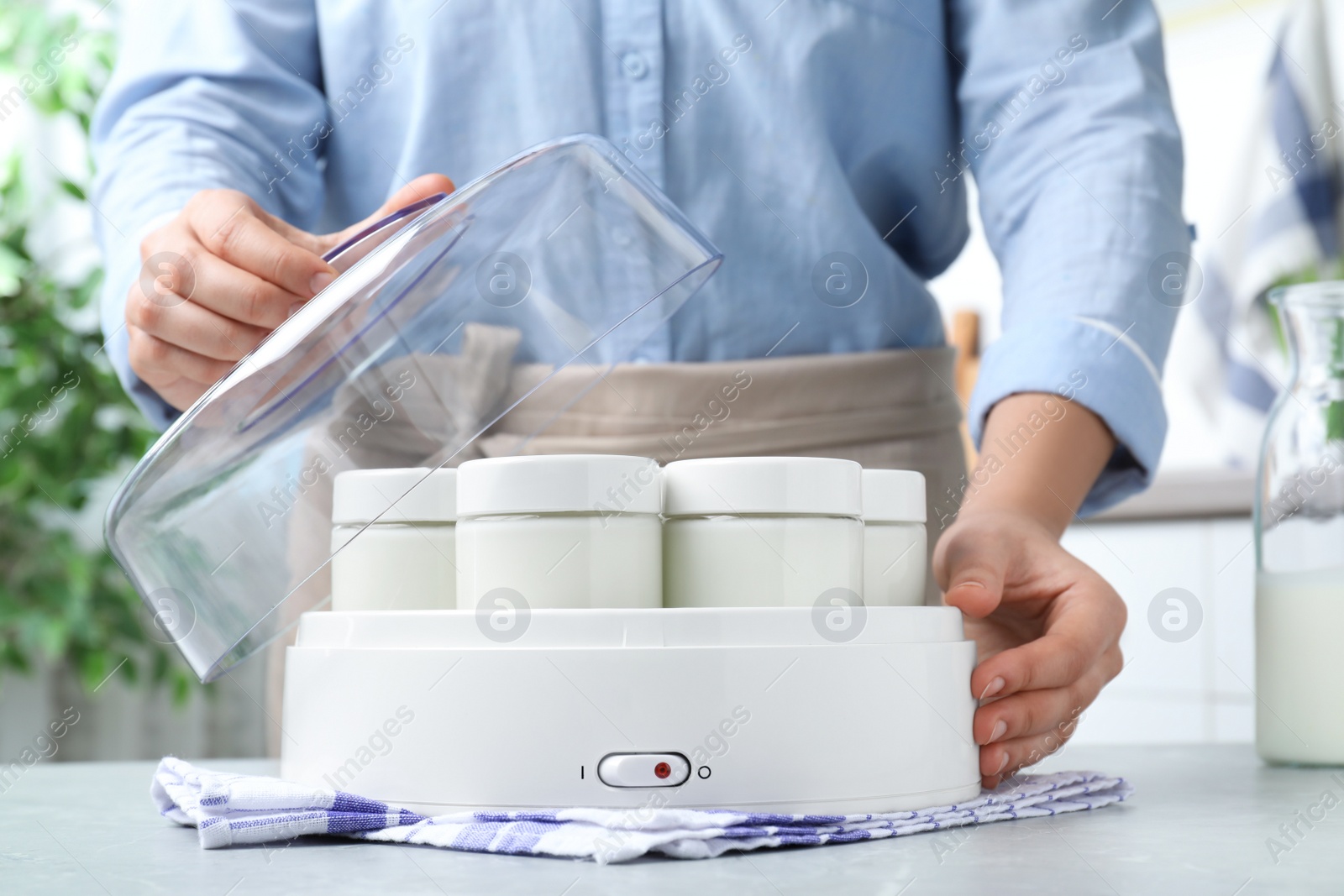 Photo of Woman making tasty yogurt at light grey table in kitchen, closeup