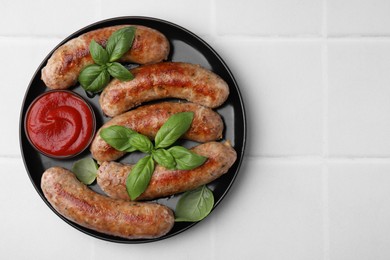 Photo of Plate with tasty homemade sausages, ketchup and basil leaves on white tiled table, top view. Space for text