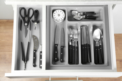 Open drawer with different utensils, top view. Order in kitchen