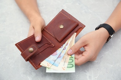 Man putting Euro banknotes in wallet, closeup