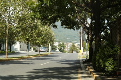 Photo of View of city street with road and lush trees