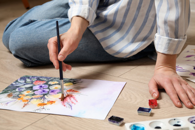 Photo of Woman painting flowers with watercolor on floor, closeup