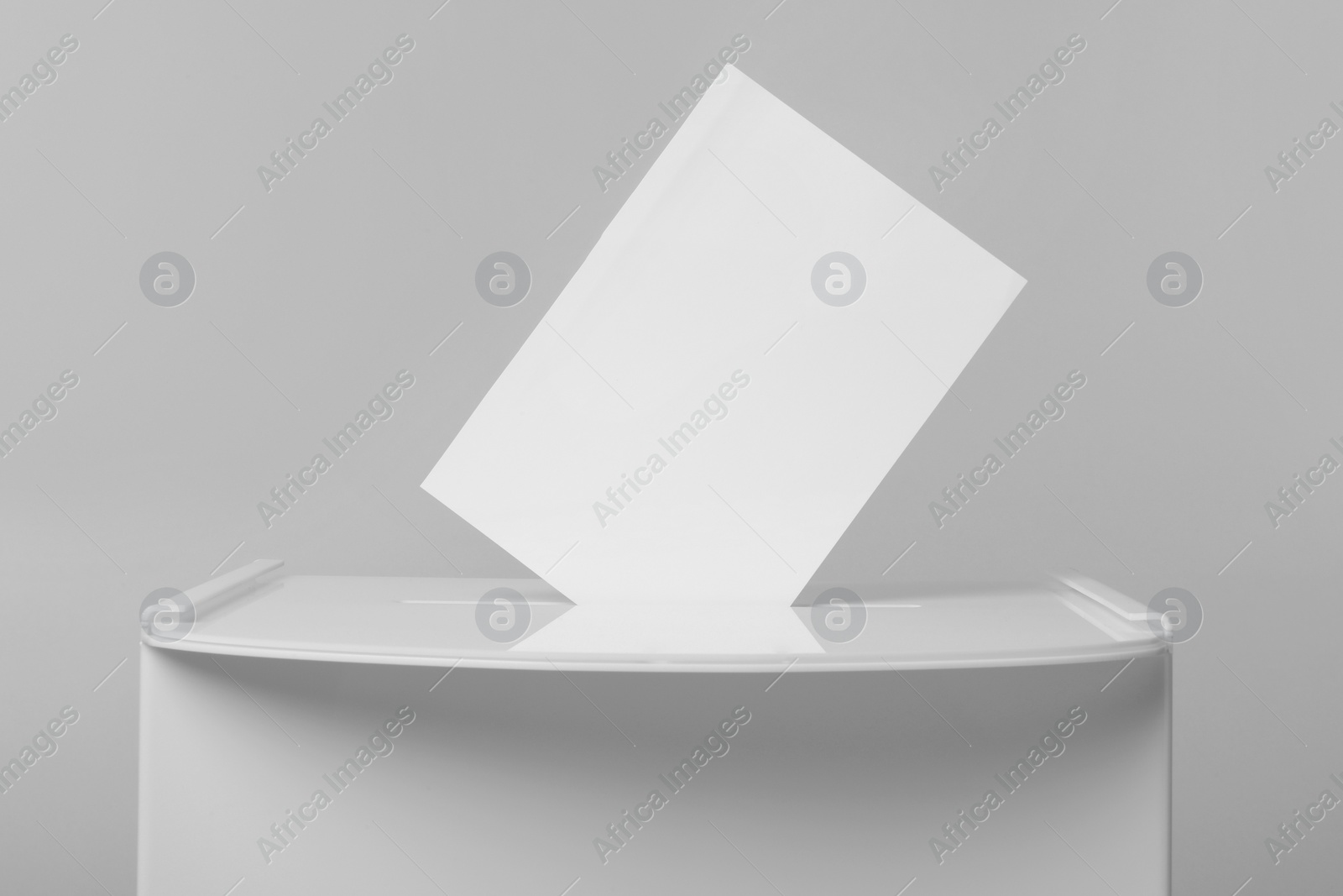 Photo of Ballot box with vote on light grey background, closeup. Election time