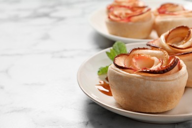 Freshly baked apple roses on white marble table, space for text. Beautiful dessert