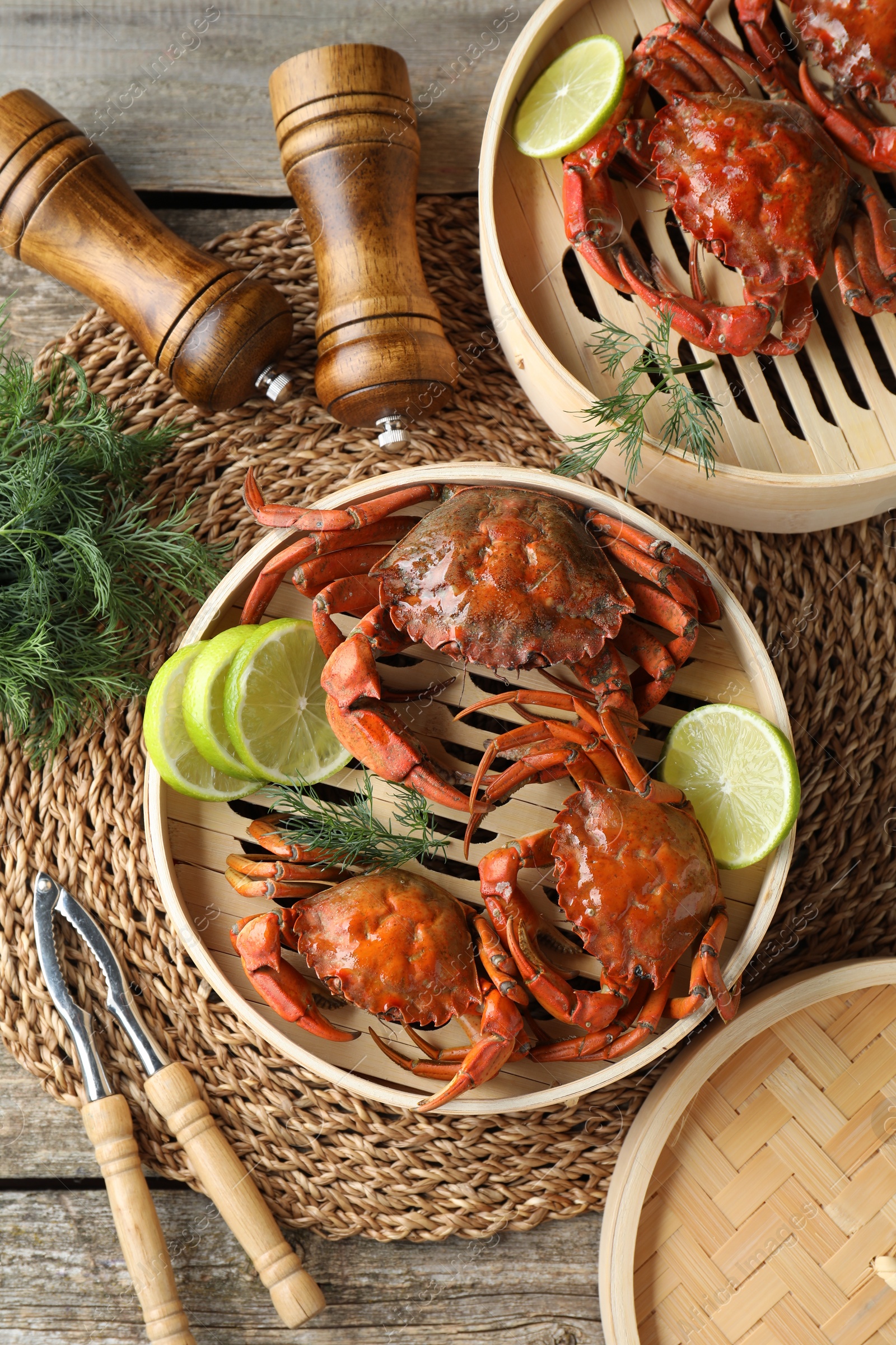 Photo of Delicious boiled crabs with lime on wooden table, flat lay