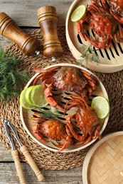 Delicious boiled crabs with lime on wooden table, flat lay