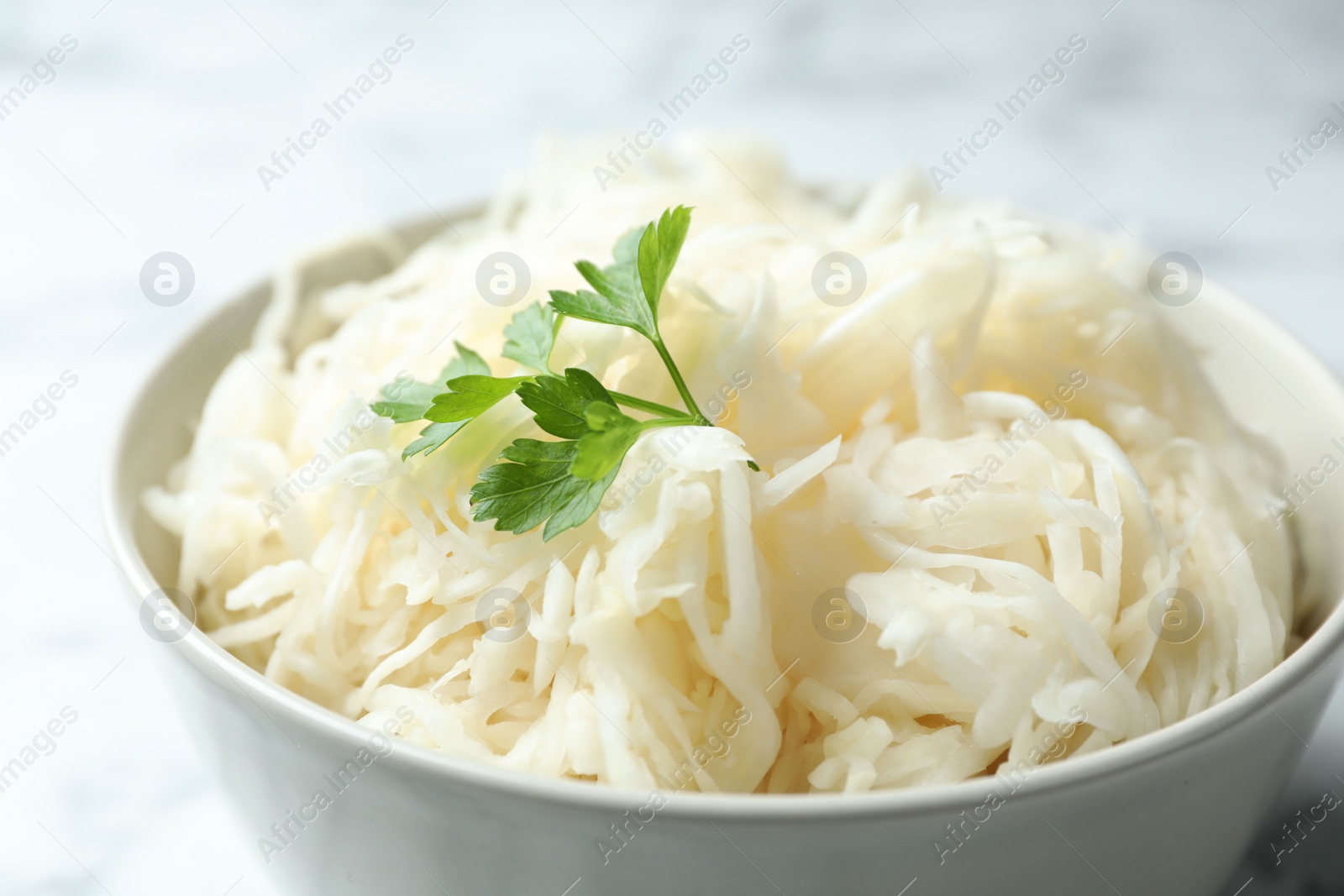 Photo of Tasty fermented cabbage with parsley on table, closeup