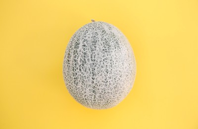 Photo of Whole fresh ripe cantaloupe melon on yellow background, top view