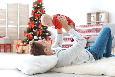 Photo of Young man with baby in Christmas suit at home