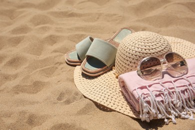 Photo of Straw hat, sunglasses, towel and slippers on sand, space for text. Beach accessories