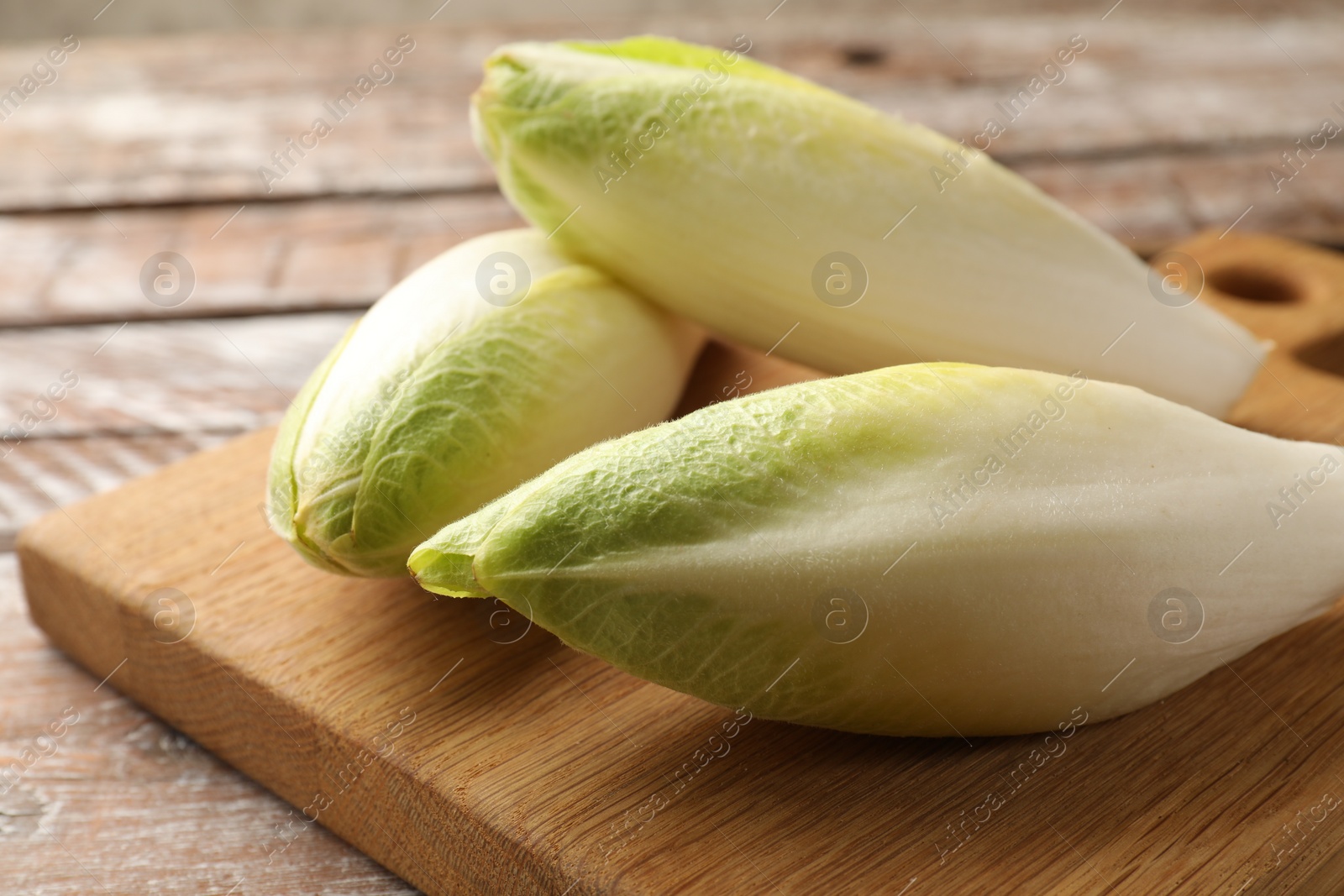 Photo of Fresh raw Belgian endives (chicory) on wooden table, closeup