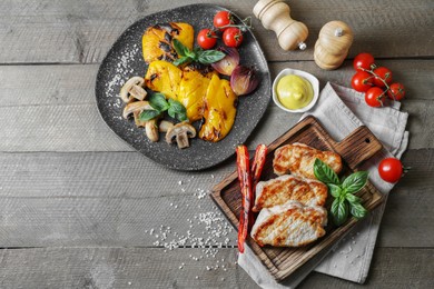 Photo of Delicious grilled meat and vegetables served on wooden table, flat lay. Space for text