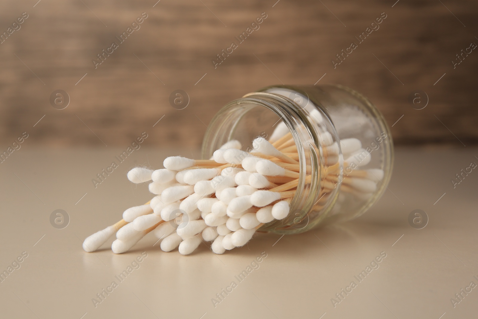 Photo of Jar and clean cotton buds on beige background, closeup