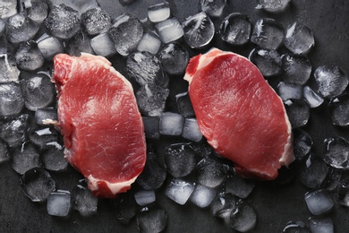 Photo of Flat lay composition with raw meat and ice cubes on dark background