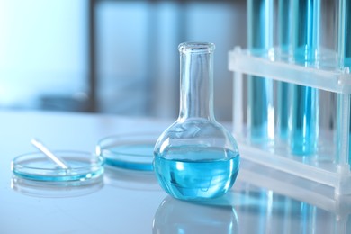 Photo of Different glassware and test tubes with light blue liquid on table in laboratory. Space for text