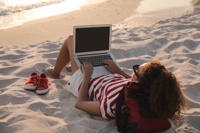 Photo of African American woman working on laptop at beach