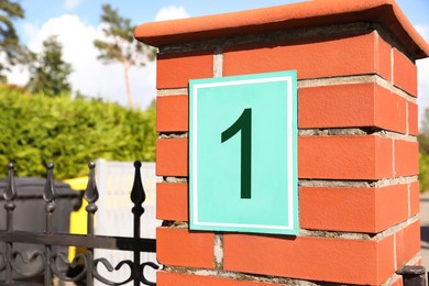 Photo of House number 1 on red brick column outdoors