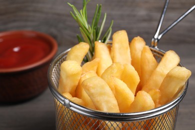 Photo of Delicious French fries with rosemary in metal basket, closeup