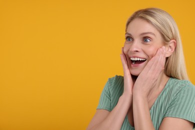 Portrait of happy surprised woman on yellow background, space for text