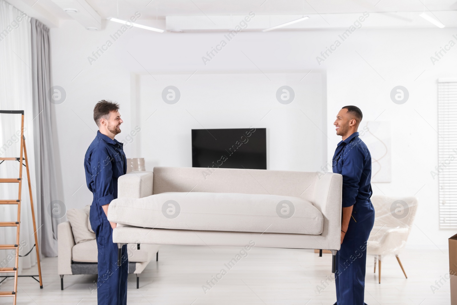 Photo of Male movers carrying sofa in new house