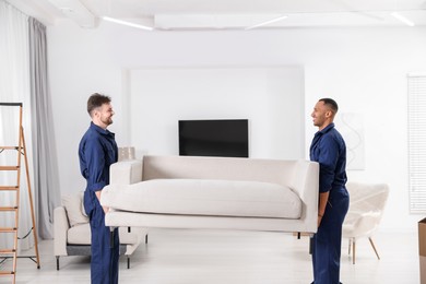 Male movers carrying sofa in new house