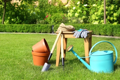 Set of gardening tools and stool on green grass