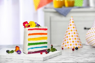 Photo of Slice of delicious rainbow cake with flowers on table