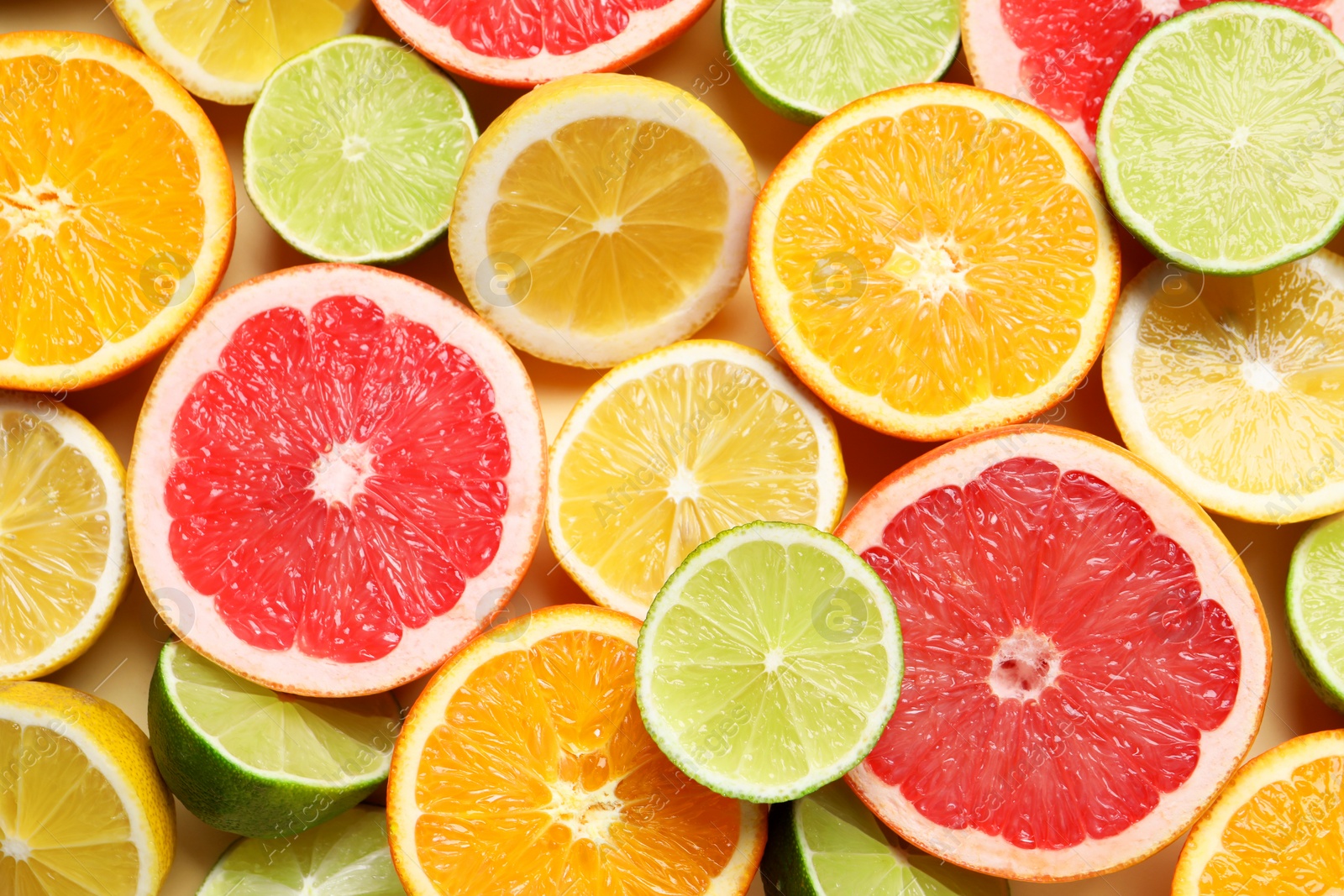 Photo of Different cut citrus fruits on beige table, flat lay