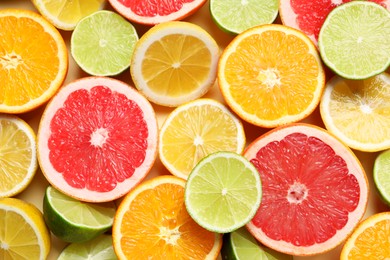 Photo of Different cut citrus fruits on beige table, flat lay