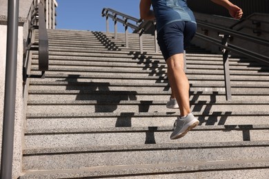 Photo of Man running up stairs outdoors on sunny day, closeup. Space for text