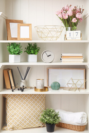 White shelving unit with plants and different decorative stuff