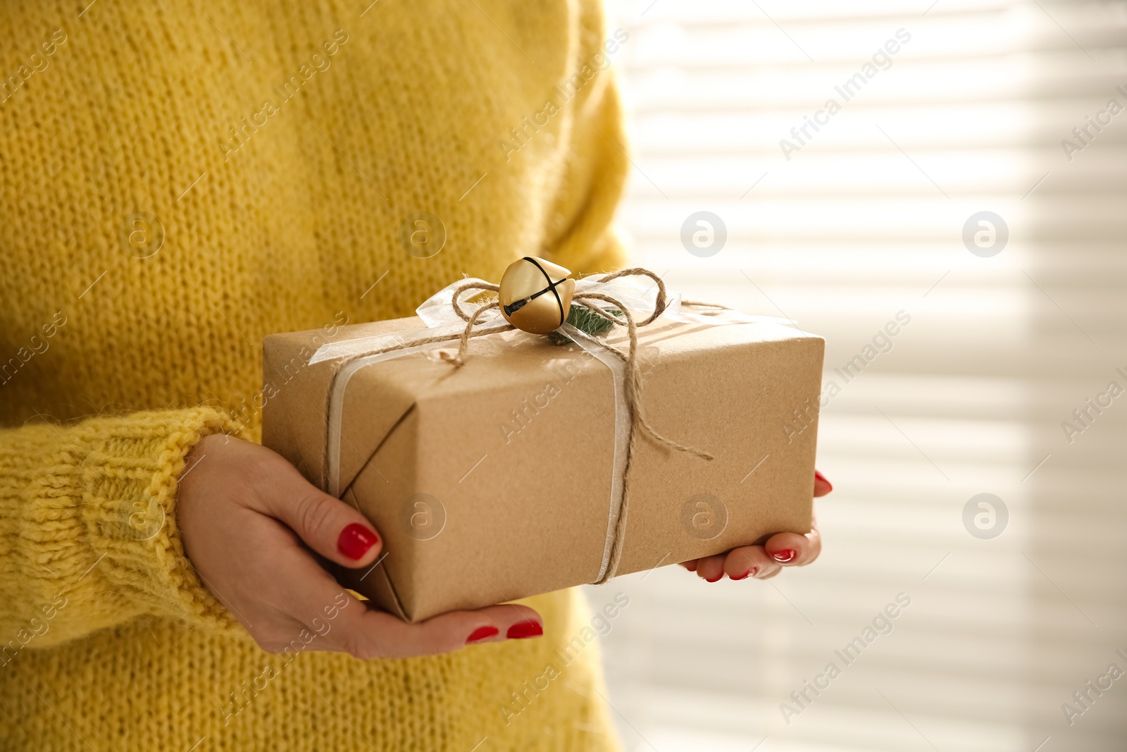 Photo of Woman holding Christmas gift box indoors, closeup