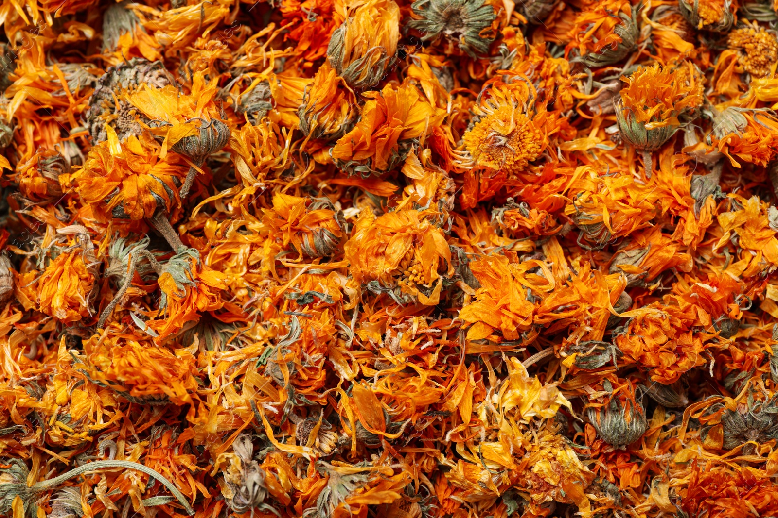 Photo of Pile of dry calendula flowers as background, top view