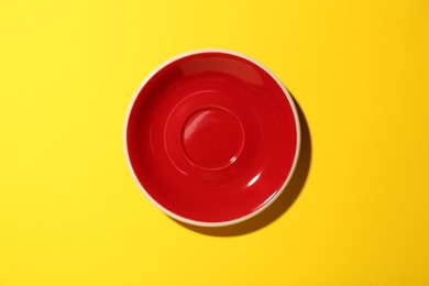 Photo of One clean plate on yellow background, top view. Ceramic dinnerware