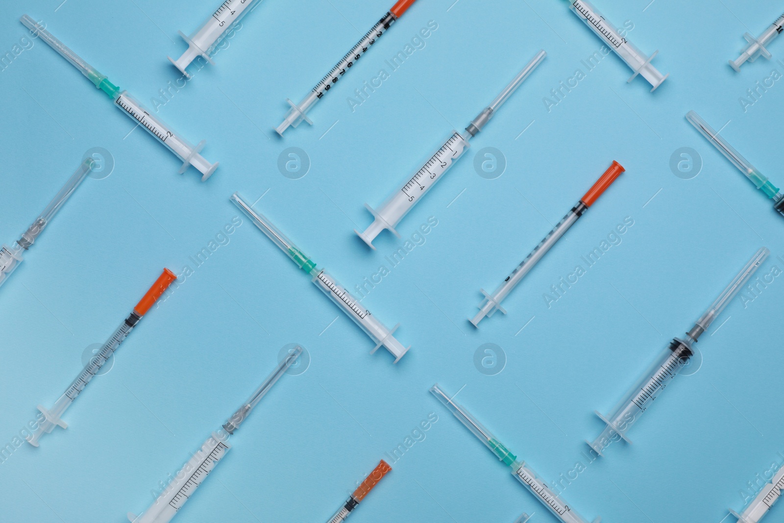 Photo of Disposable syringes with needles on light blue background, flat lay