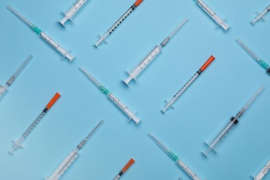Disposable syringes with needles on light blue background, flat lay