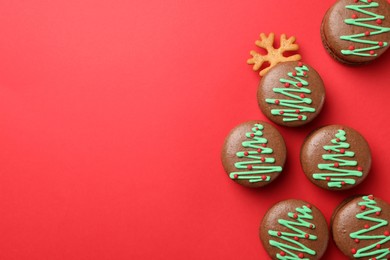 Photo of Beautifully decorated Christmas macarons on red background, flat lay. Space for text