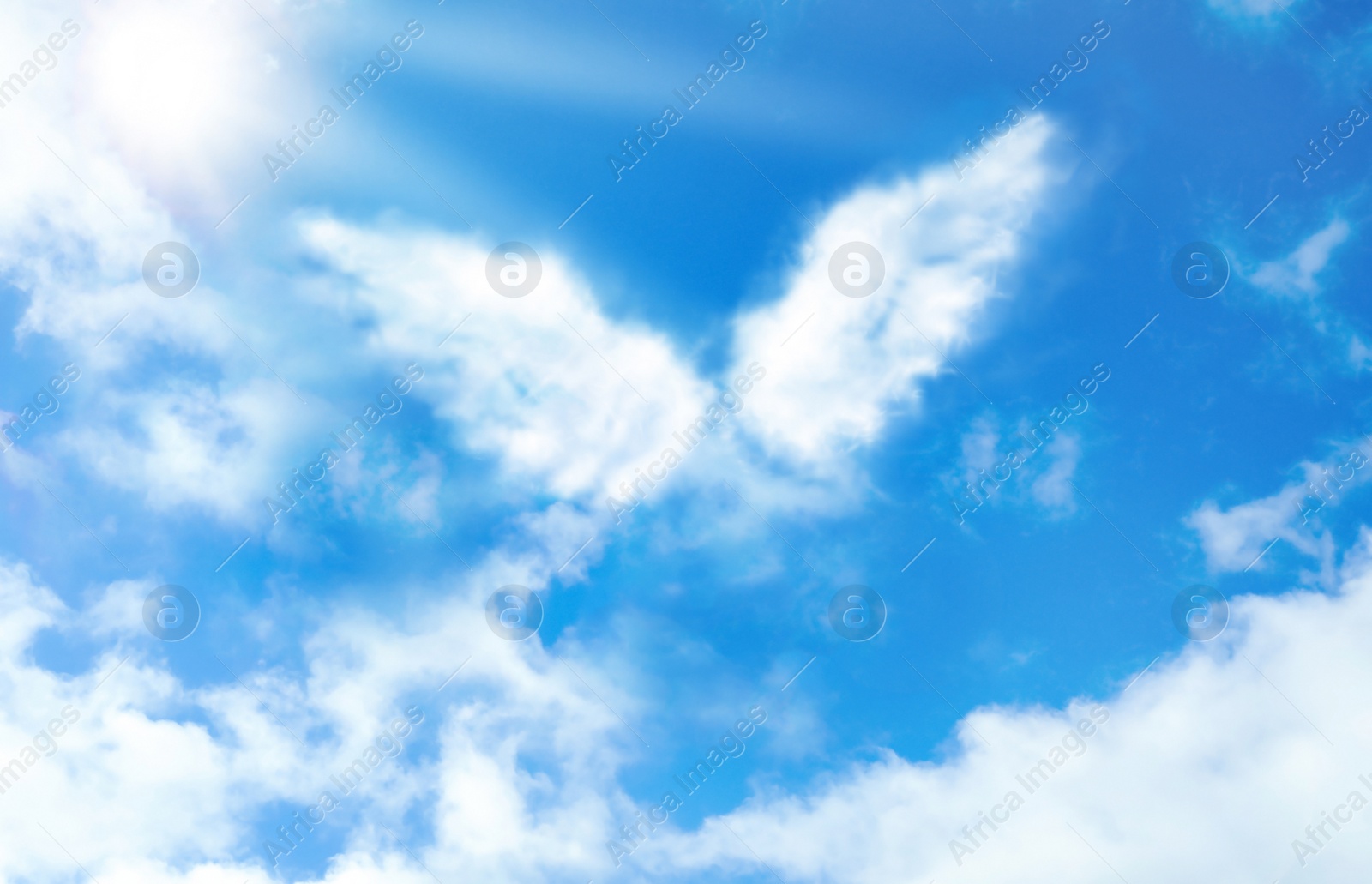 Image of Silhouette of angel's wings made of clouds in blue sky 