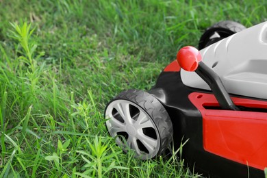 Photo of Cutting green grass with lawn mower in garden, closeup. Space for text