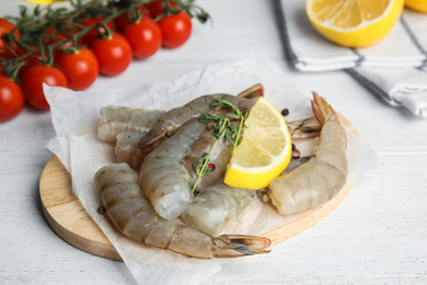 Photo of Fresh raw shrimps with lemon and thyme on white wooden table