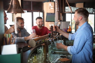 Photo of Friends drinking beer at counter in bar
