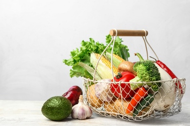 Photo of Fresh vegetables and metal basket on wooden table