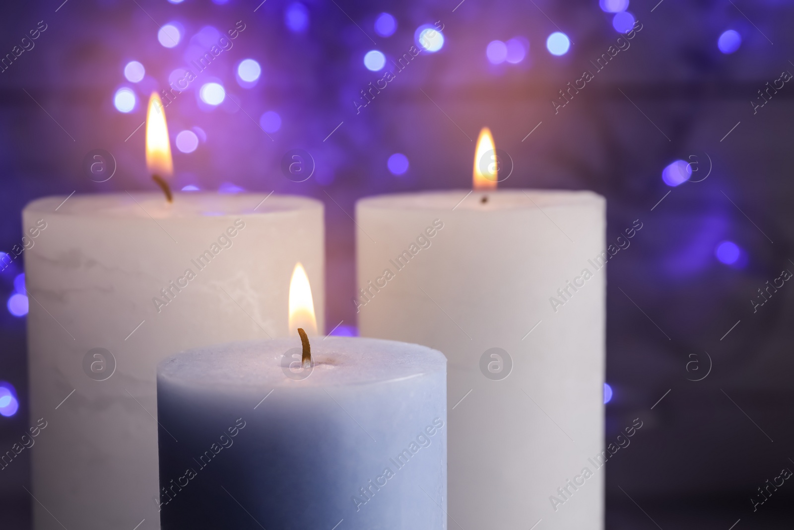 Photo of Burning wax candles on blurred background, closeup