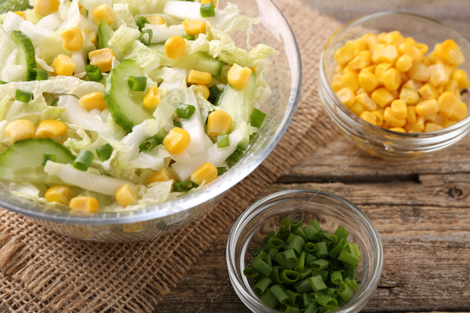 Photo of Tasty salad with Chinese cabbage, corn and green onion on wooden table, closeup