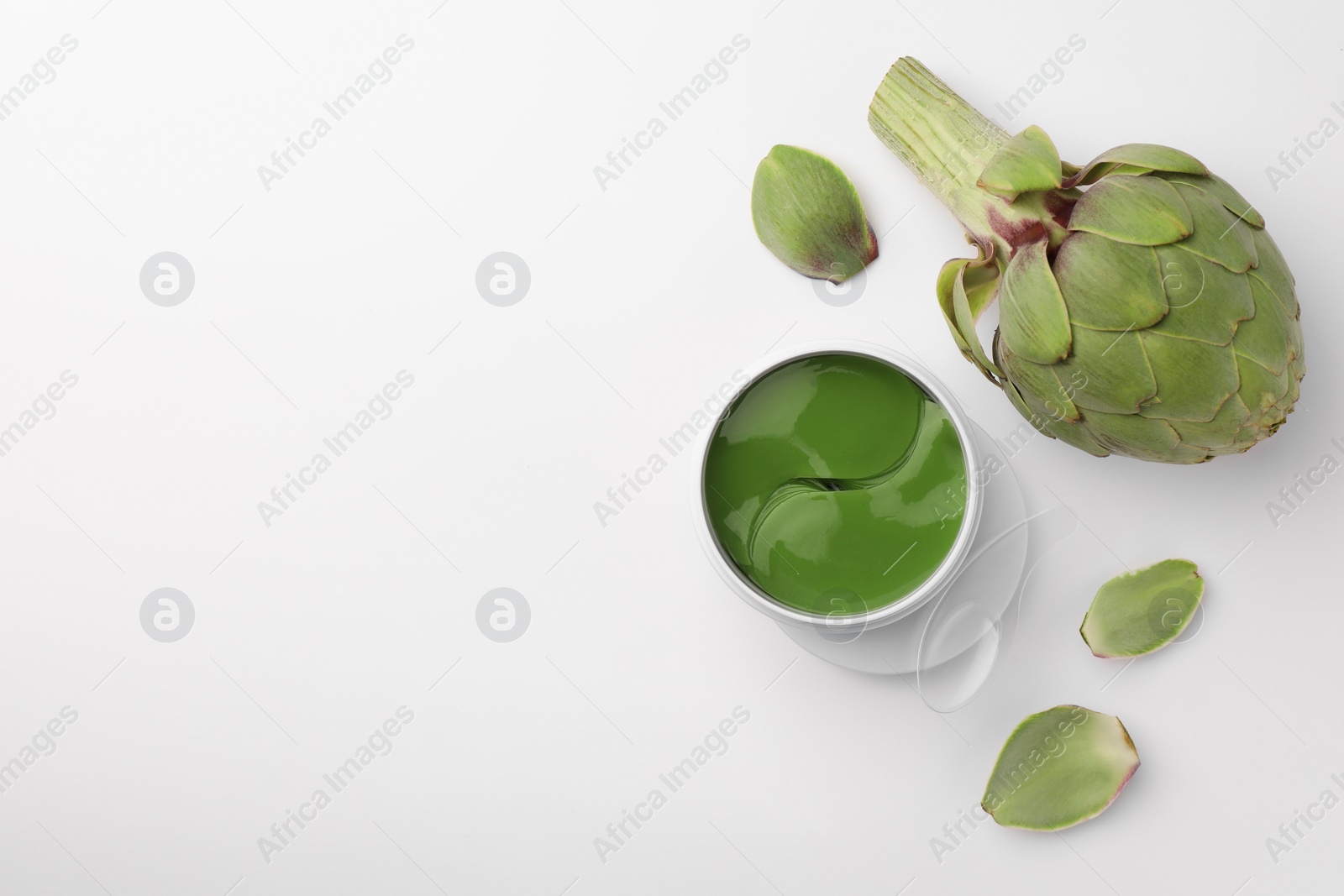 Photo of Package of under eye patches and artichokes on white background, top view. Cosmetic product