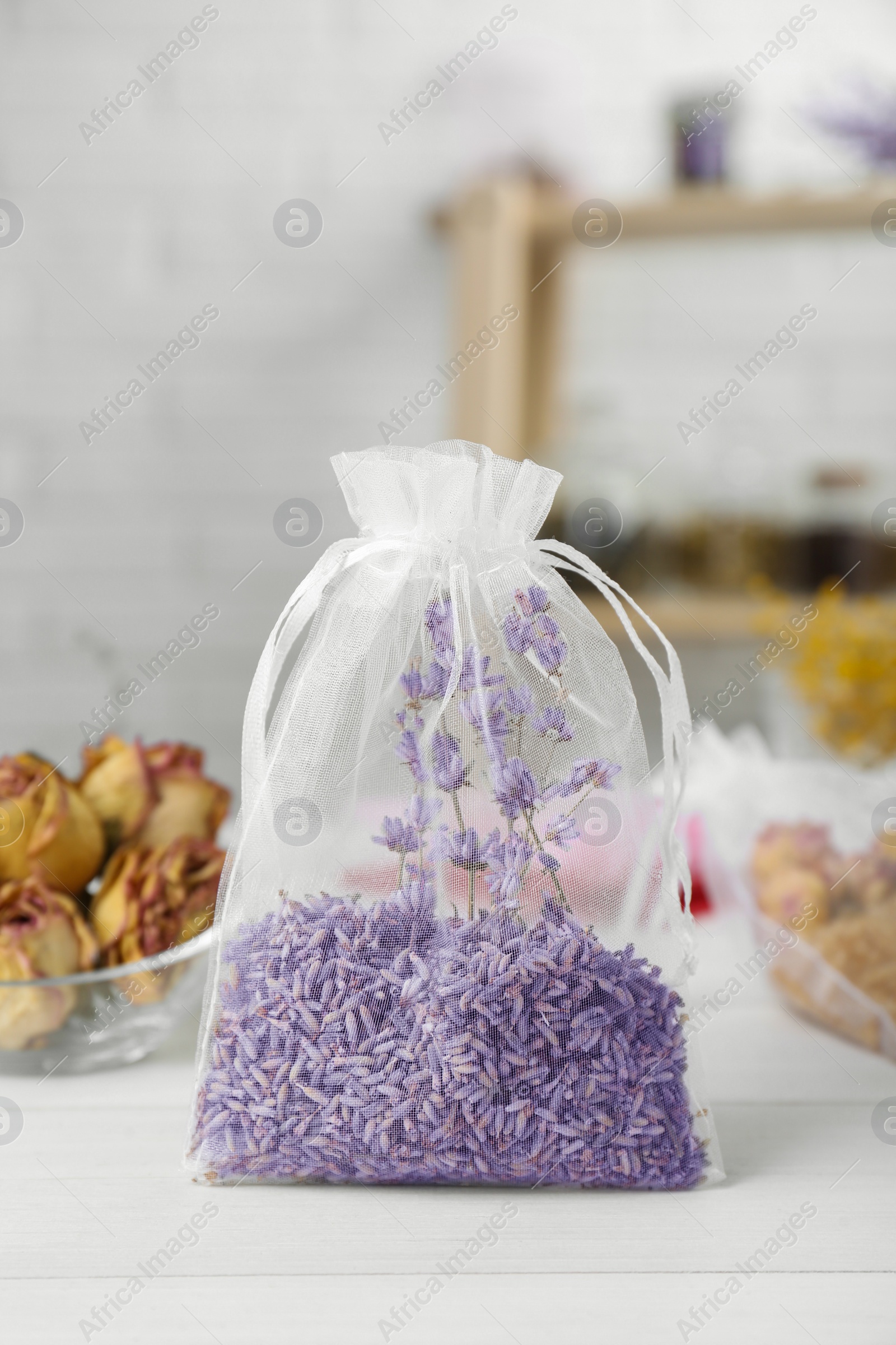 Photo of Scented sachet with dried lavender flowers on white table