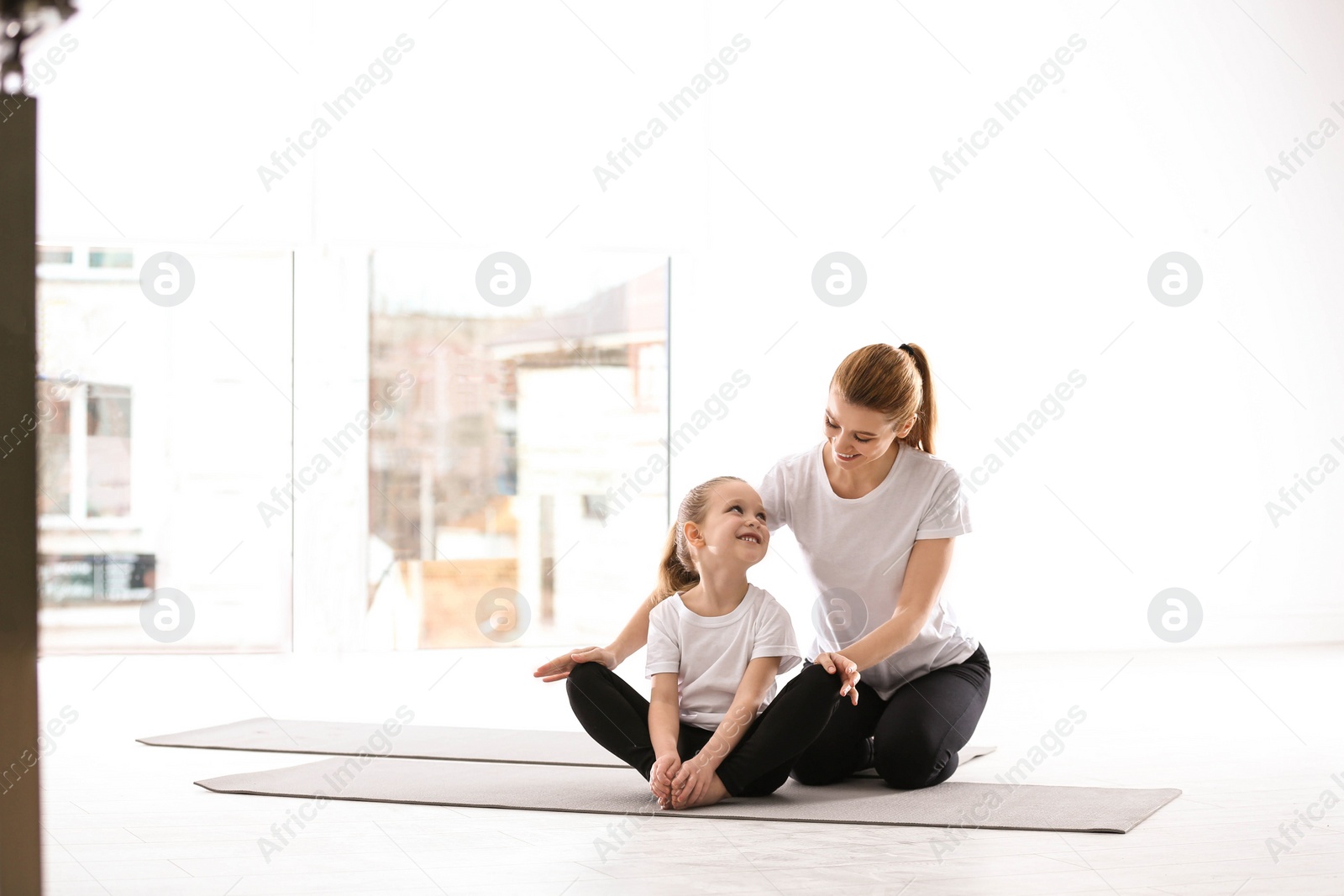 Photo of Mother and daughter in matching sportswear doing yoga together at home