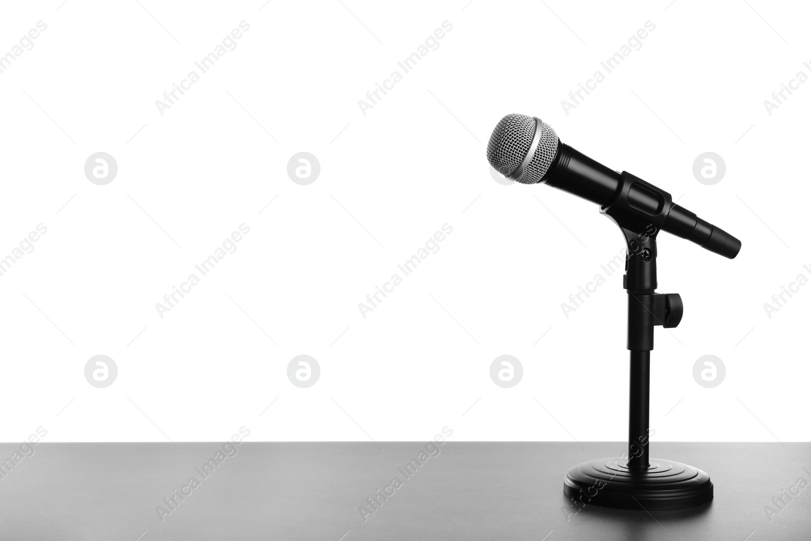 Photo of Modern microphone on table against white background. Space for text